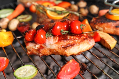 Barbecue grill with delicious cooked meat and vegetables, closeup