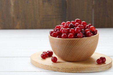 Photo of Fresh ripe cranberries in bowl on white wooden table, closeup. Space for text