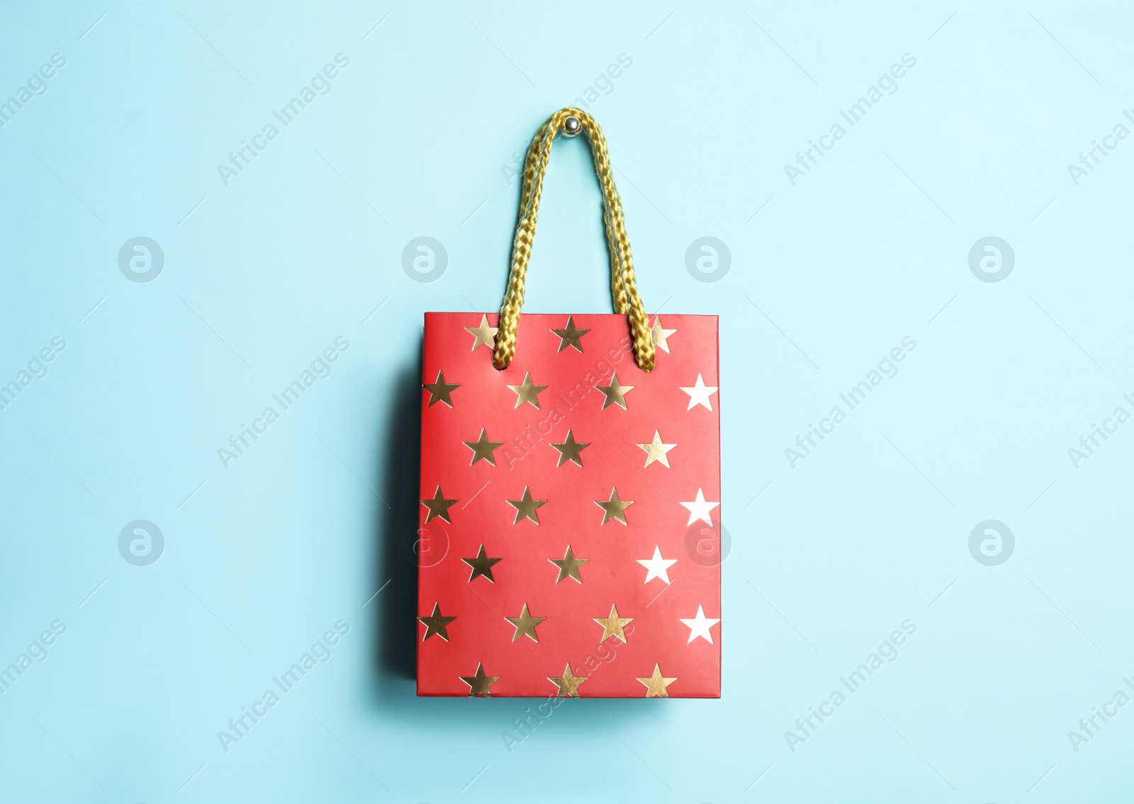 Photo of Red shopping paper bag with star pattern on light blue background