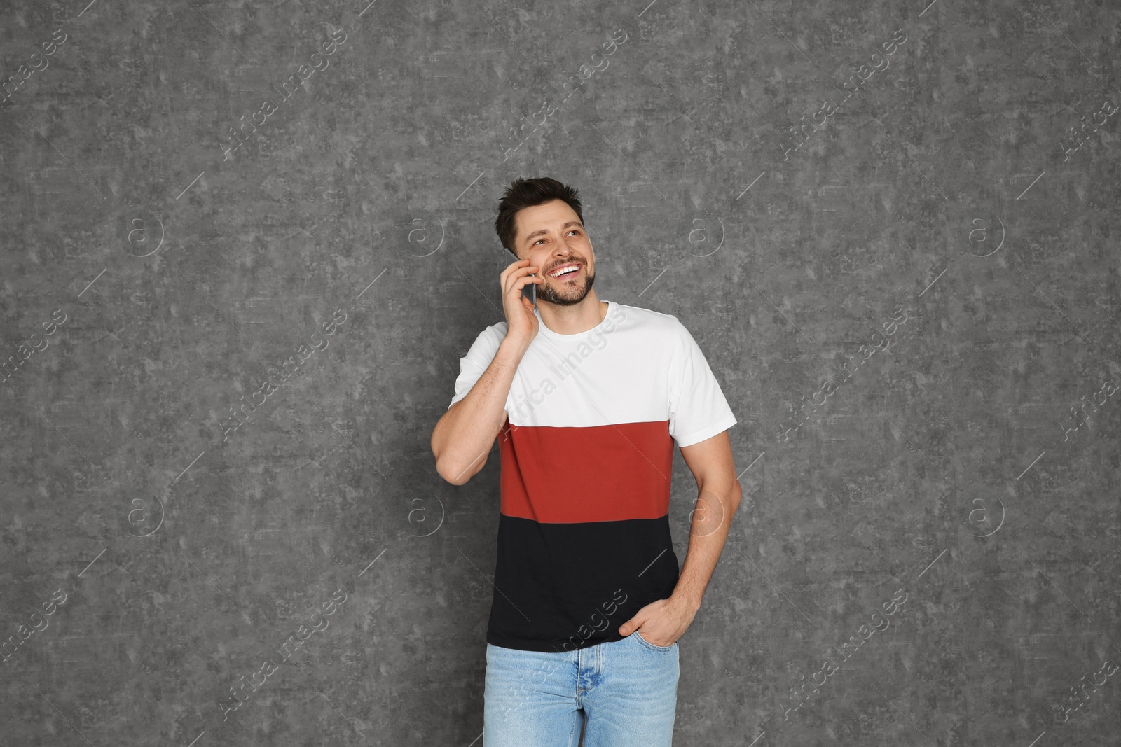 Photo of Portrait of man talking on mobile phone against grey background