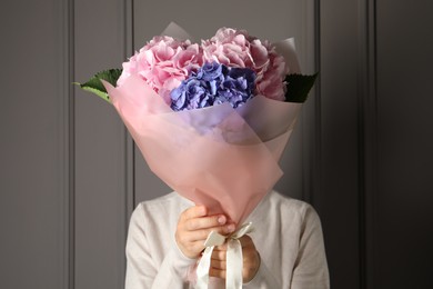 Photo of Woman with bouquet of beautiful hortensia flowers near grey wall