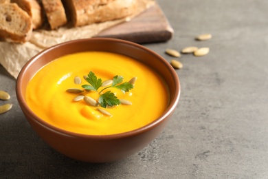 Delicious pumpkin cream soup in bowl on gray background. Space for text