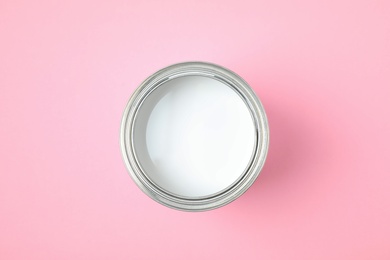 Photo of Open can of white paint on pink background, top view