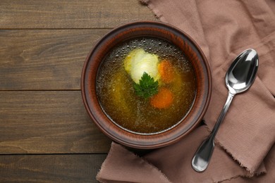 Delicious chicken bouillon with carrot and parsley in bowl on wooden table, flat lay