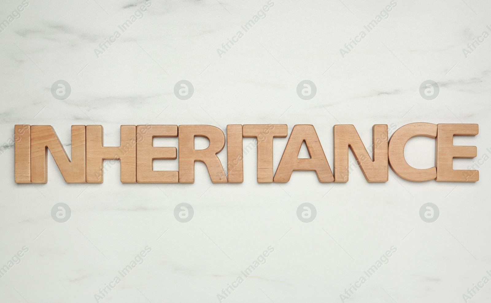 Photo of Word Inheritance made with wooden letters on white marble background, flat lay