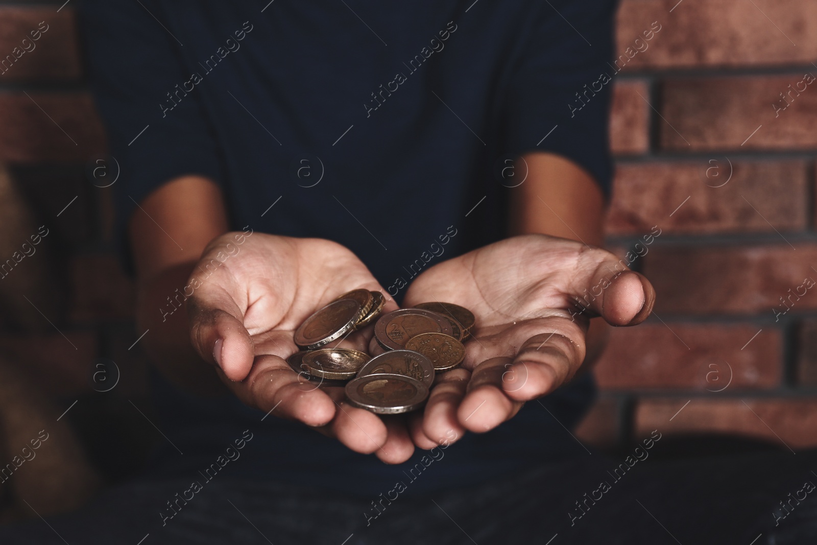 Image of Poor homeless boy begging near brick wall, focus on hands