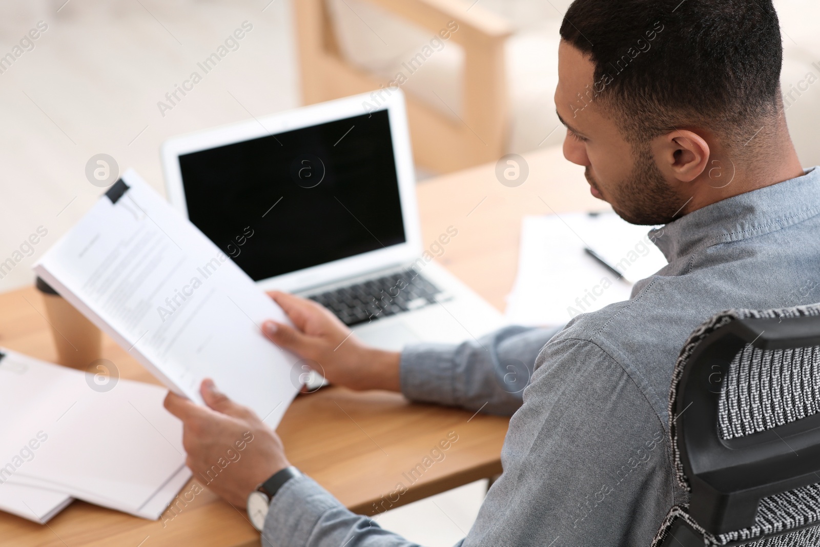 Photo of Businessman working with documents at wooden table in office