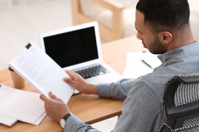 Businessman working with documents at wooden table in office