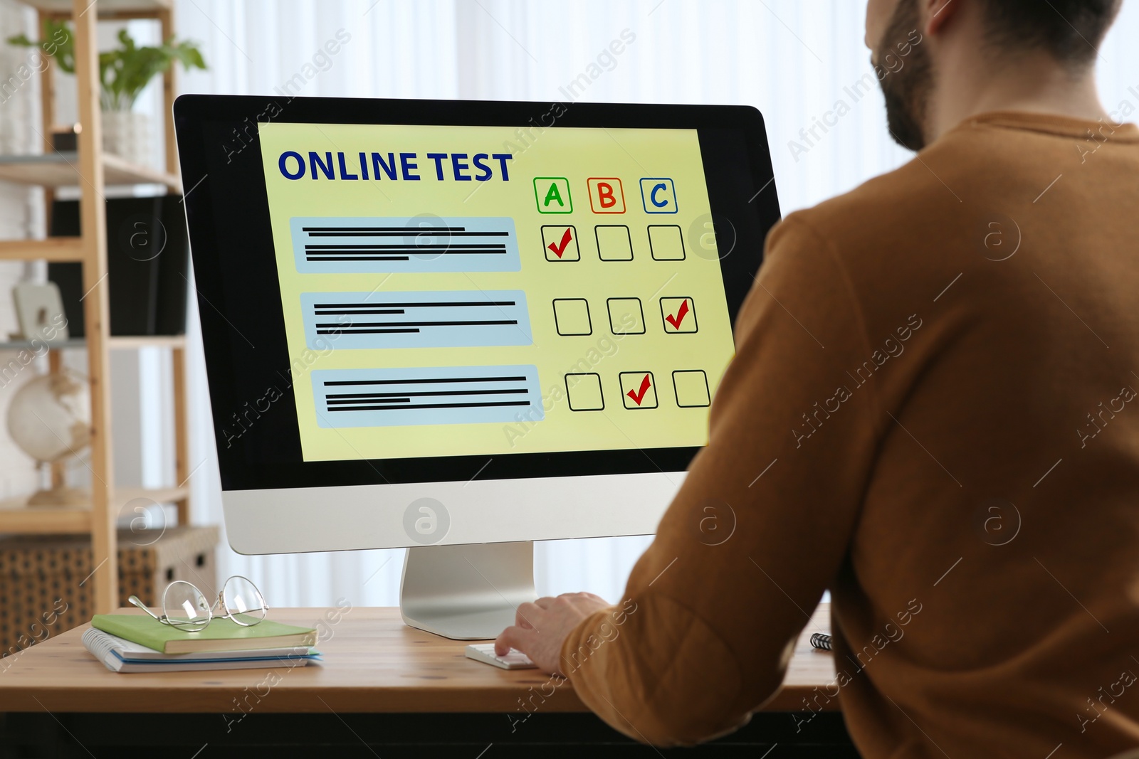 Photo of Man taking online test on computer at desk indoors, closeup