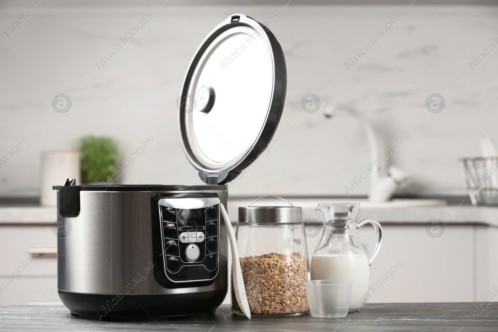 Photo of Modern multi cooker, oatmeal and milk on table in kitchen. Space for text