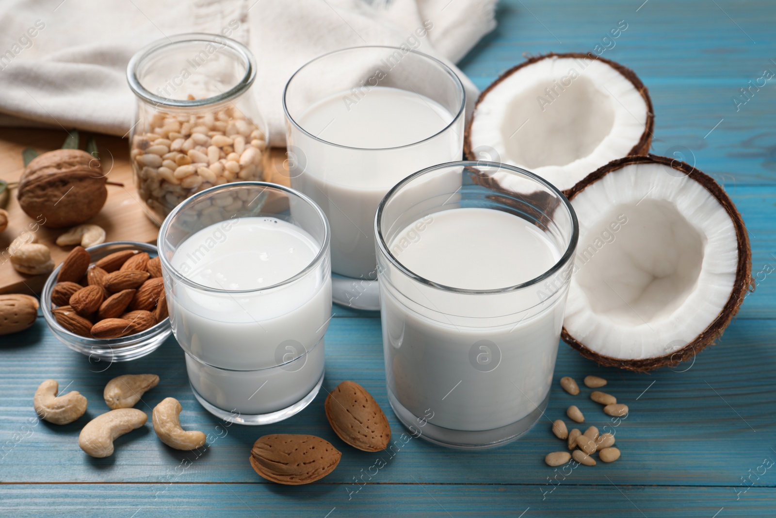 Photo of Different nut milks on light blue wooden table