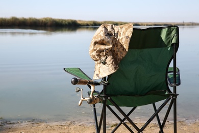 Photo of Camping chair with fishing rod at riverside on sunny day