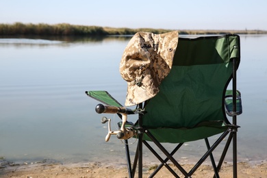 Camping chair with fishing rod at riverside on sunny day