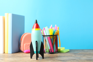 Bright toy rocket and school supplies on wooden table