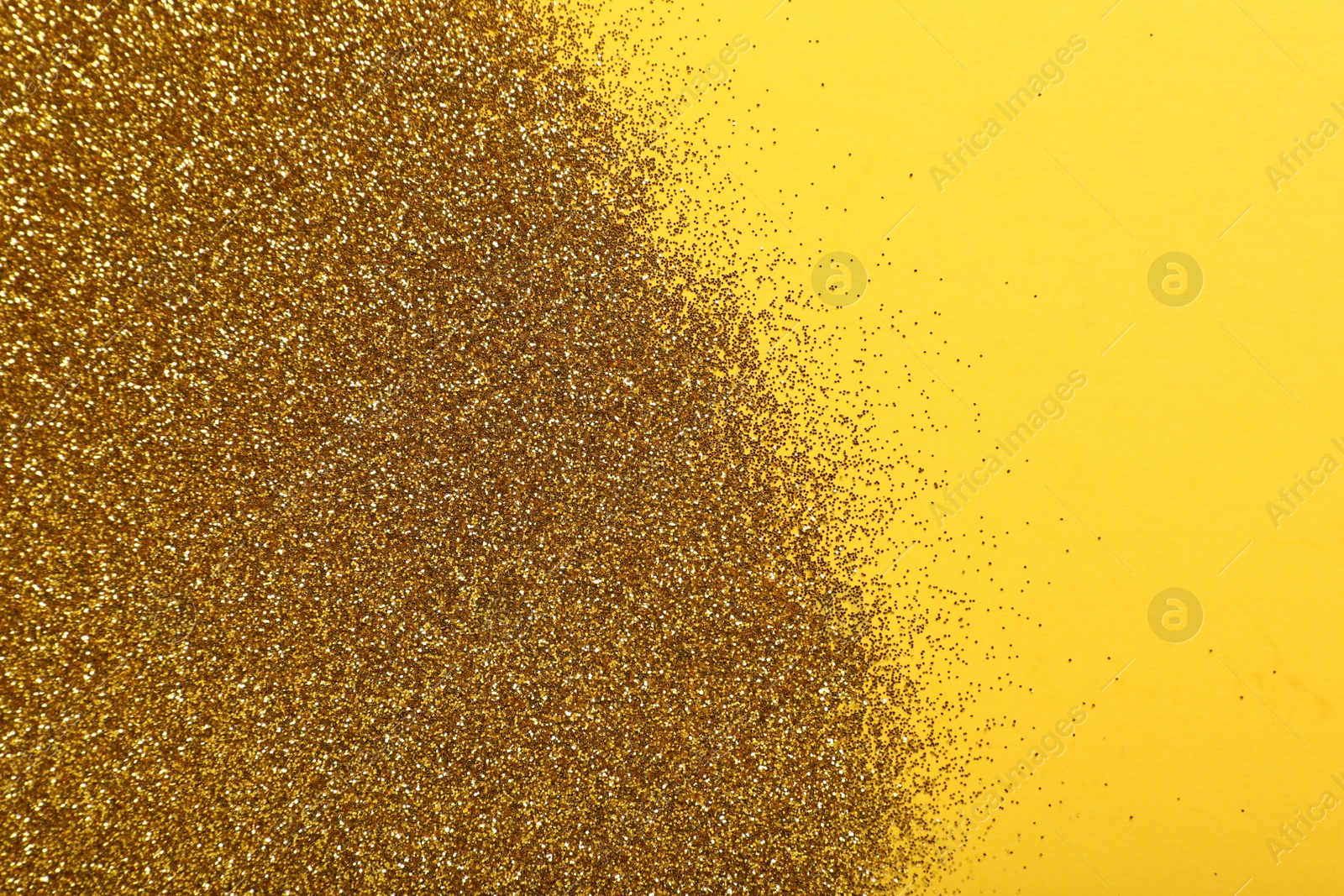 Photo of Shiny golden glitter on yellow background, top view. Space for text