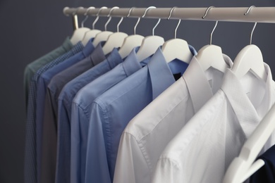 Wardrobe rack with men's clothes on grey background, closeup