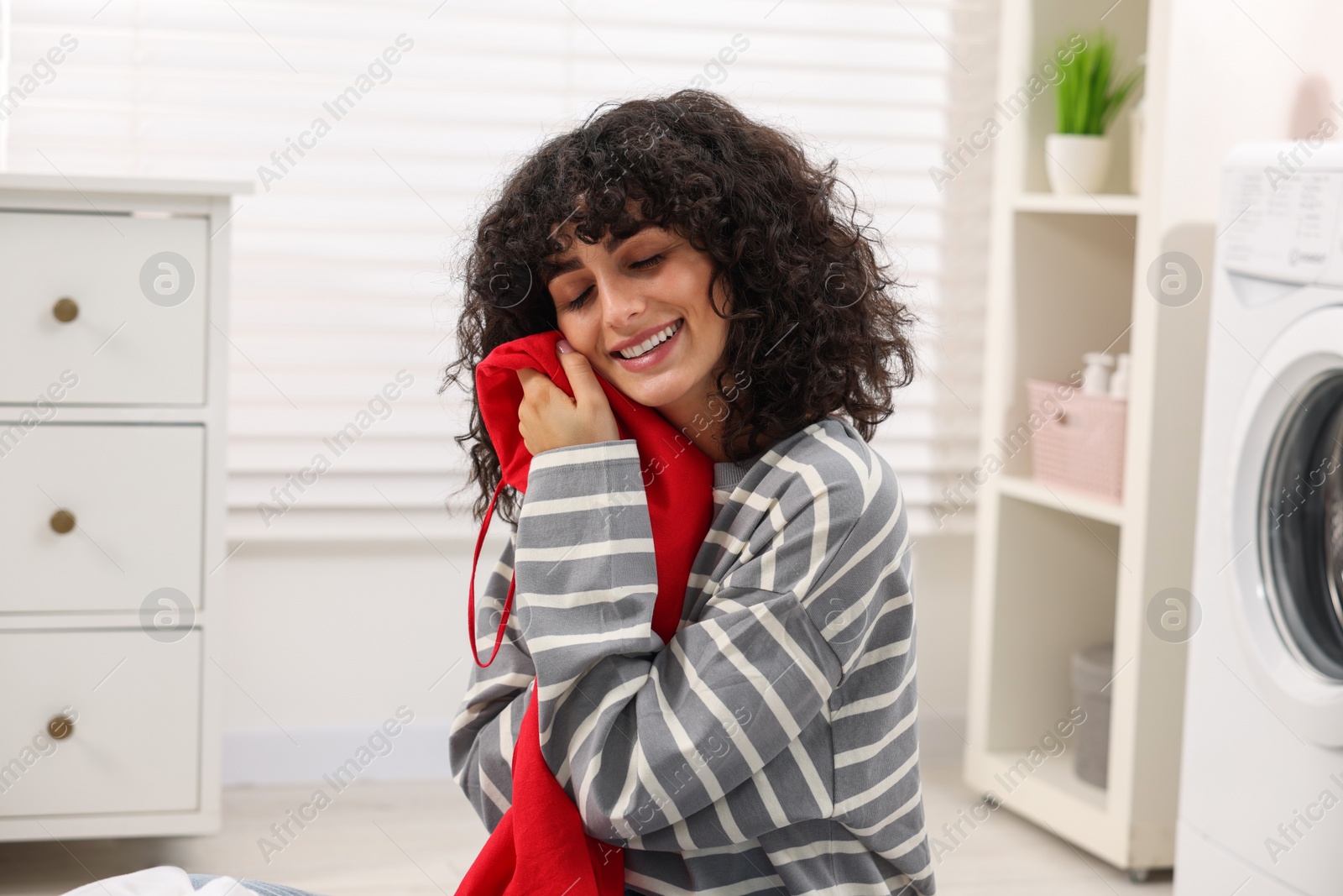 Photo of Beautiful woman with clean laundry at home