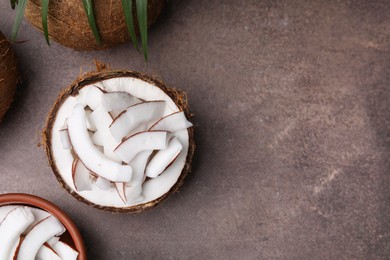 Photo of Coconut pieces in nut shell on brown table, flat lay. Space for text