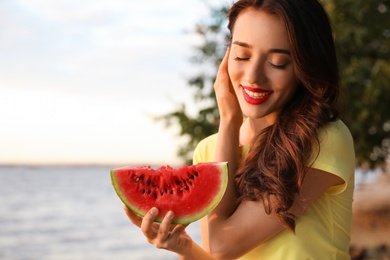 Photo of Beautiful young woman with watermelon near river