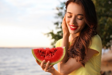 Beautiful young woman with watermelon near river