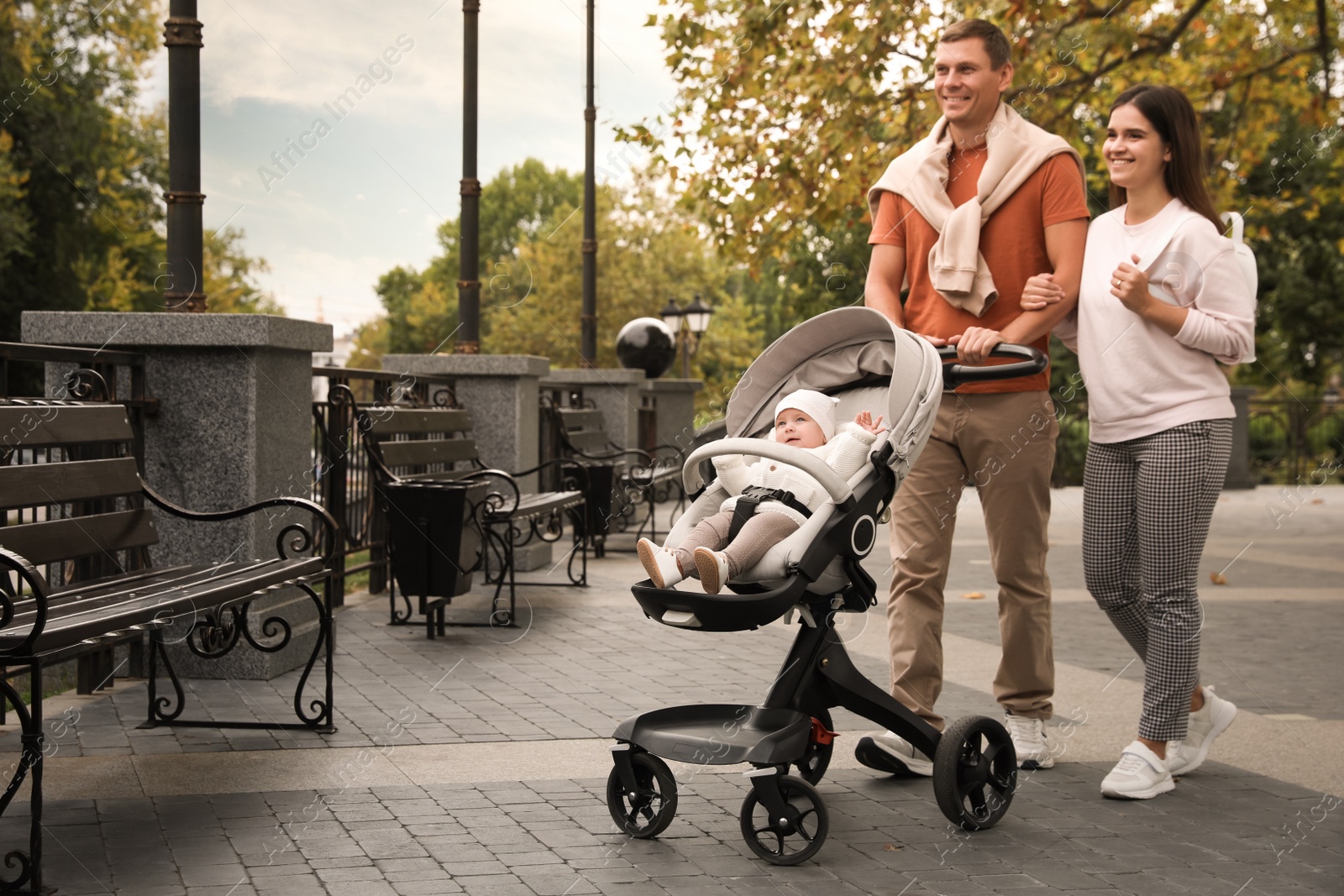 Photo of Happy parents walking with their adorable baby in stroller outdoors