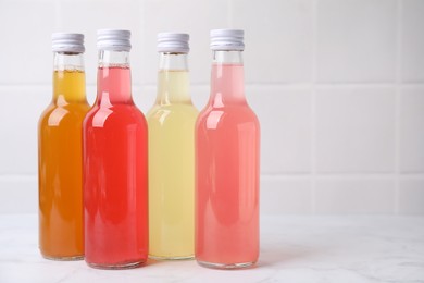 Delicious kombucha in glass bottles on white marble table, space for text