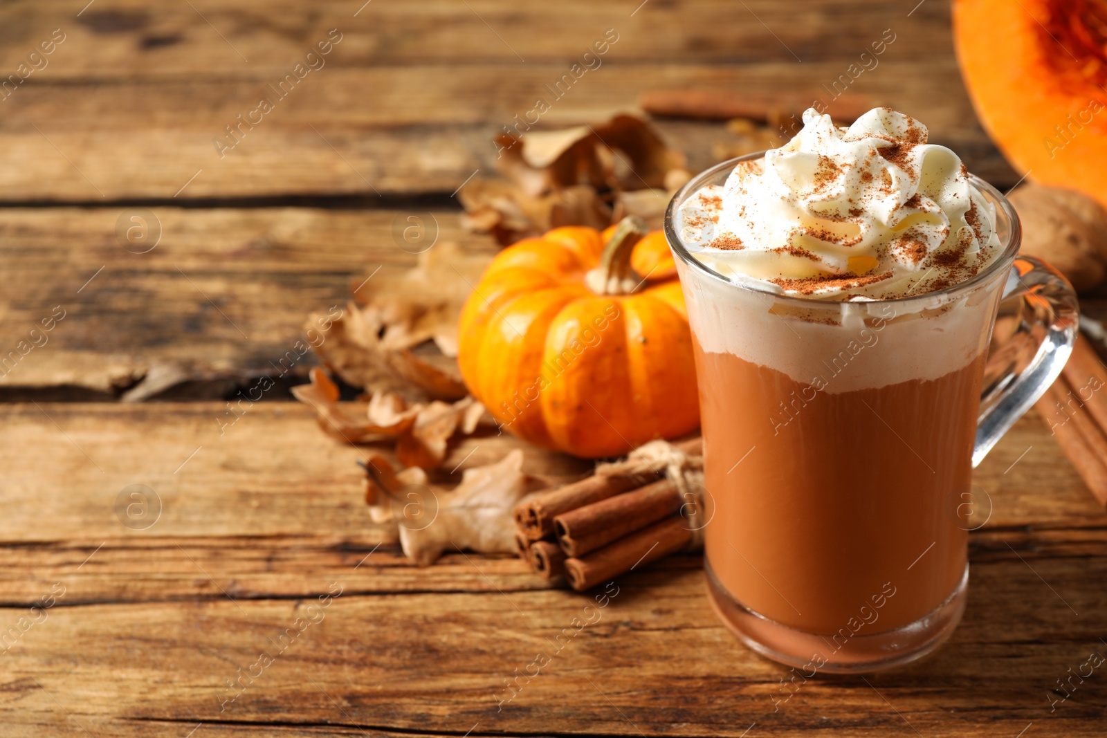Photo of Delicious pumpkin latte on wooden table, closeup. Space for text