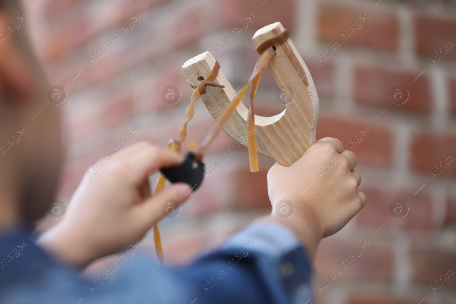 Photo of Little girl playing with slingshot outdoors, closeup