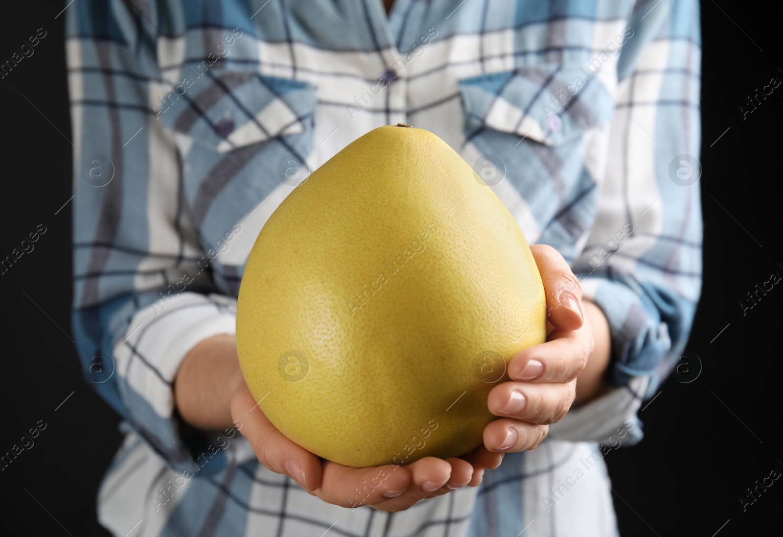 Photo of Woman holding fresh whole pomelo on black background, closeup