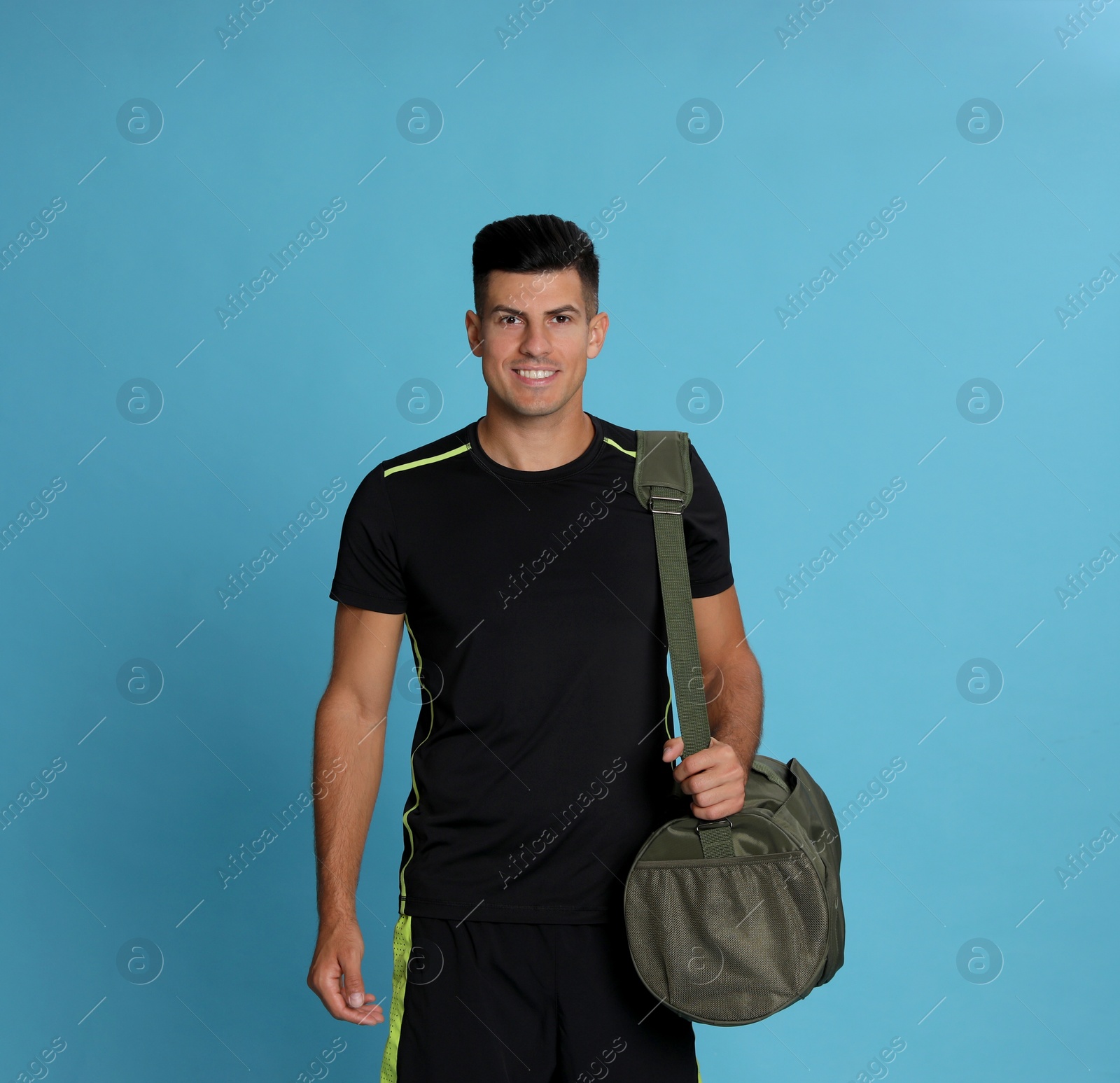 Photo of Handsome man with sports bag on light blue background