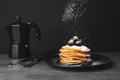 Photo of Delicious pancakes with berries and powdered sugar served for breakfast on table