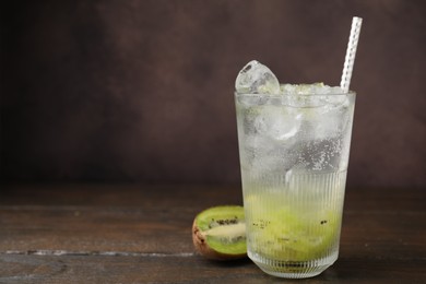 Photo of Glass of refreshing drink and cut kiwi on wooden table, space for text