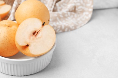 Bowl with delicious apple pears on white table, closeup. Space for text