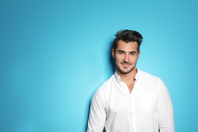 Young man with trendy hairstyle posing on color background