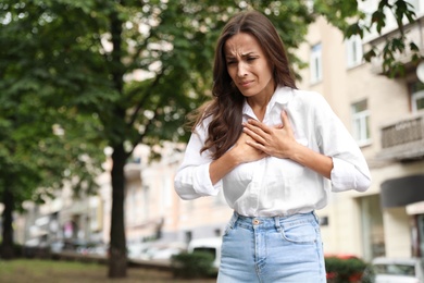 Young woman having heart attack on city street. Space for text