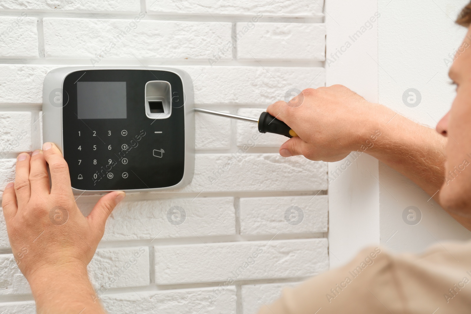 Photo of Male technician installing security alarm system indoors, closeup