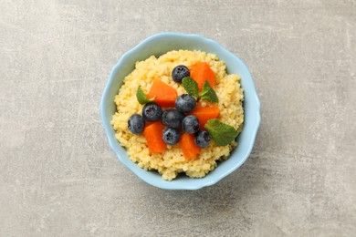 Photo of Tasty millet porridge with blueberries, pumpkin and mint in bowl on light grey table, top view