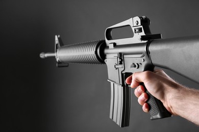 Photo of Assault gun. Man aiming rifle on dark background, closeup