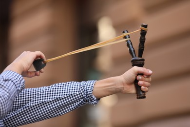 Photo of Little boy playing with slingshot outdoors, closeup