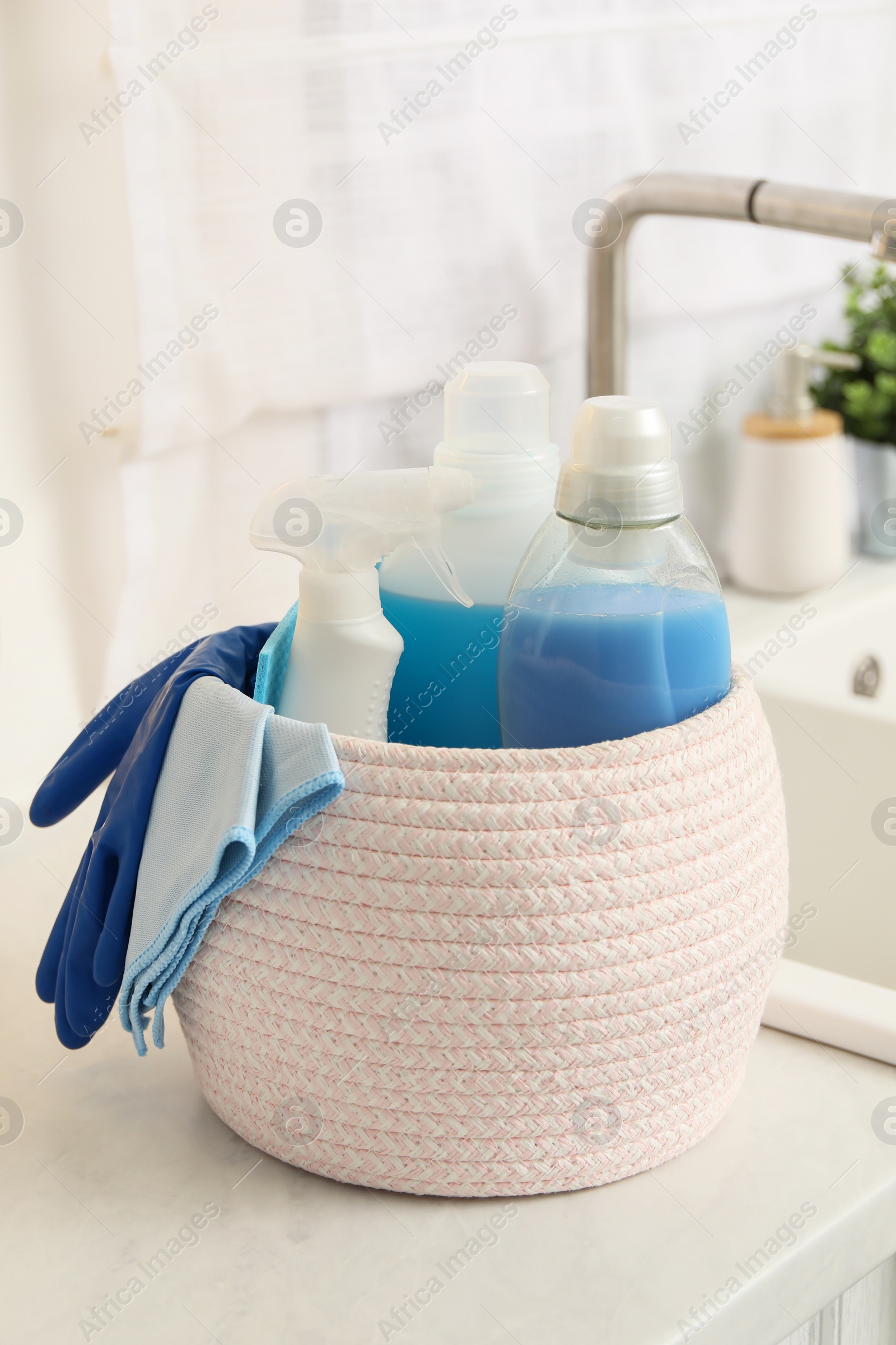 Photo of Different cleaning supplies in basket on countertop