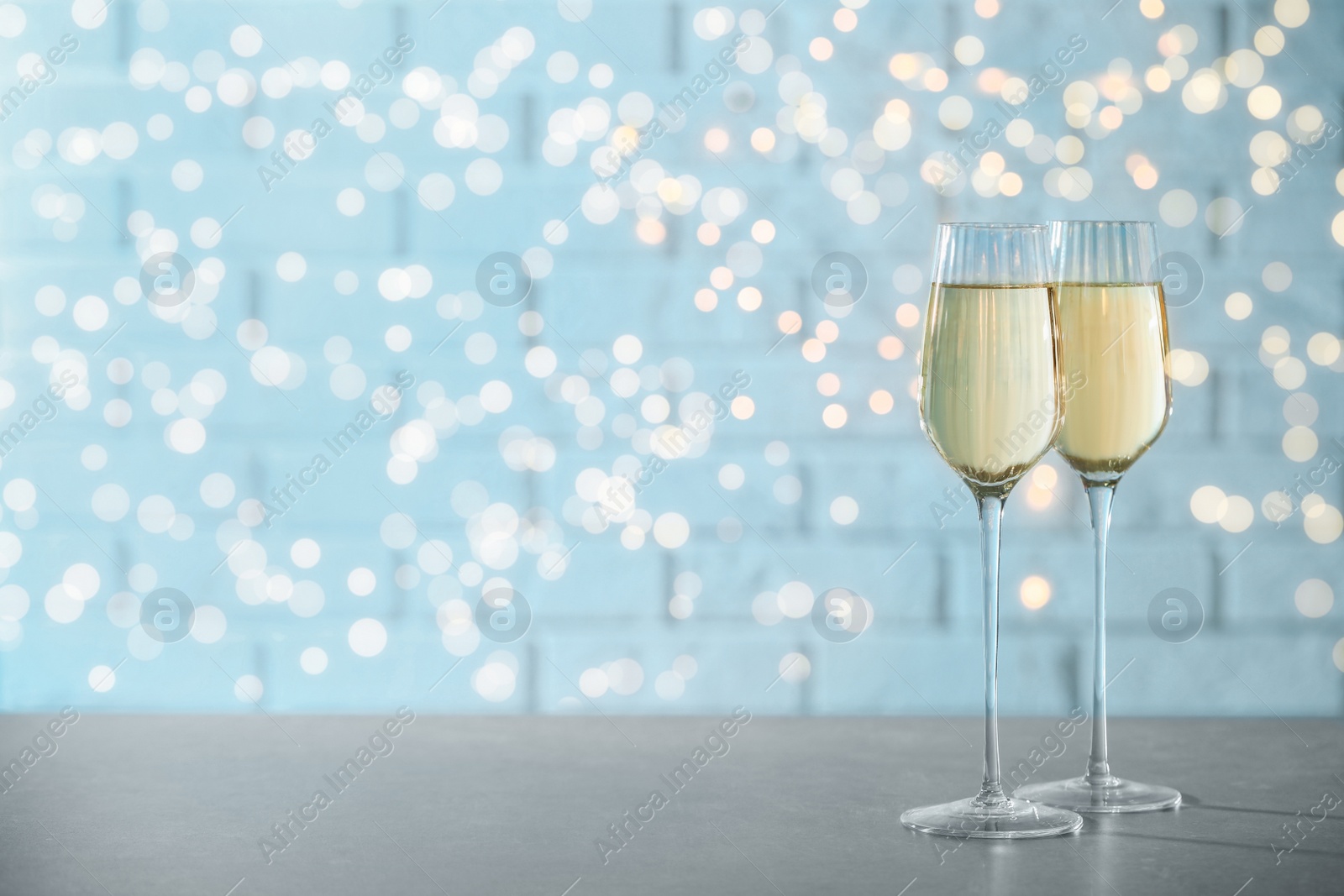 Photo of Glasses of champagne on grey table. Space for text