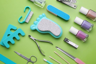 Photo of Set of pedicure tools on light green background, flat lay