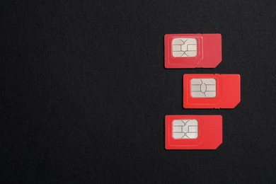 Red SIM cards on black background, flat lay. Space for text