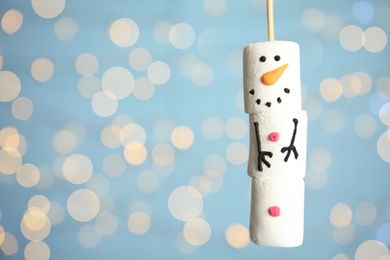 Photo of Funny snowman made of marshmallows against blurred festive lights, closeup. Space for text