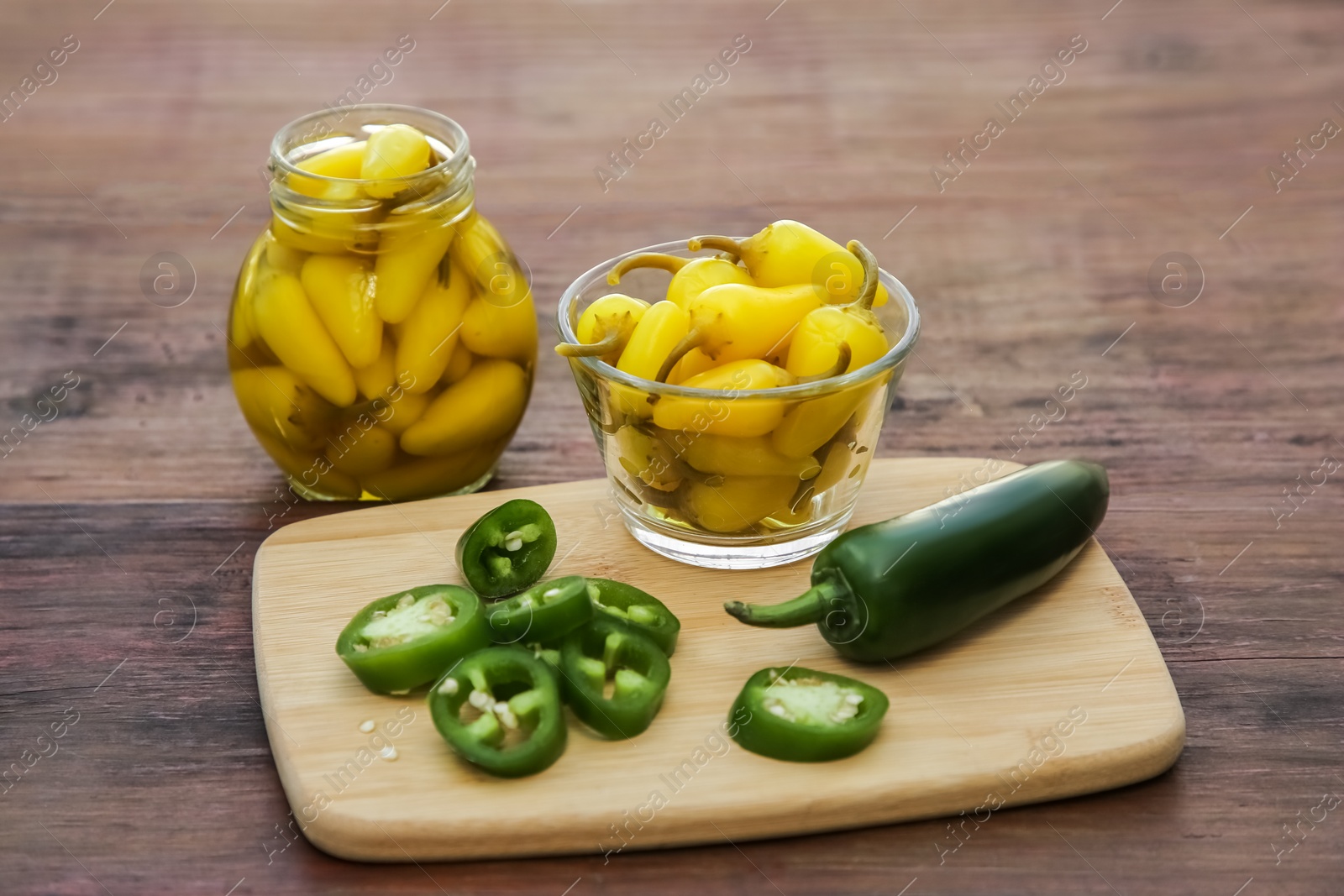 Photo of Fresh and pickled jalapeno peppers on wooden table