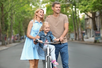 Happy family with bicycle outdoors on summer day