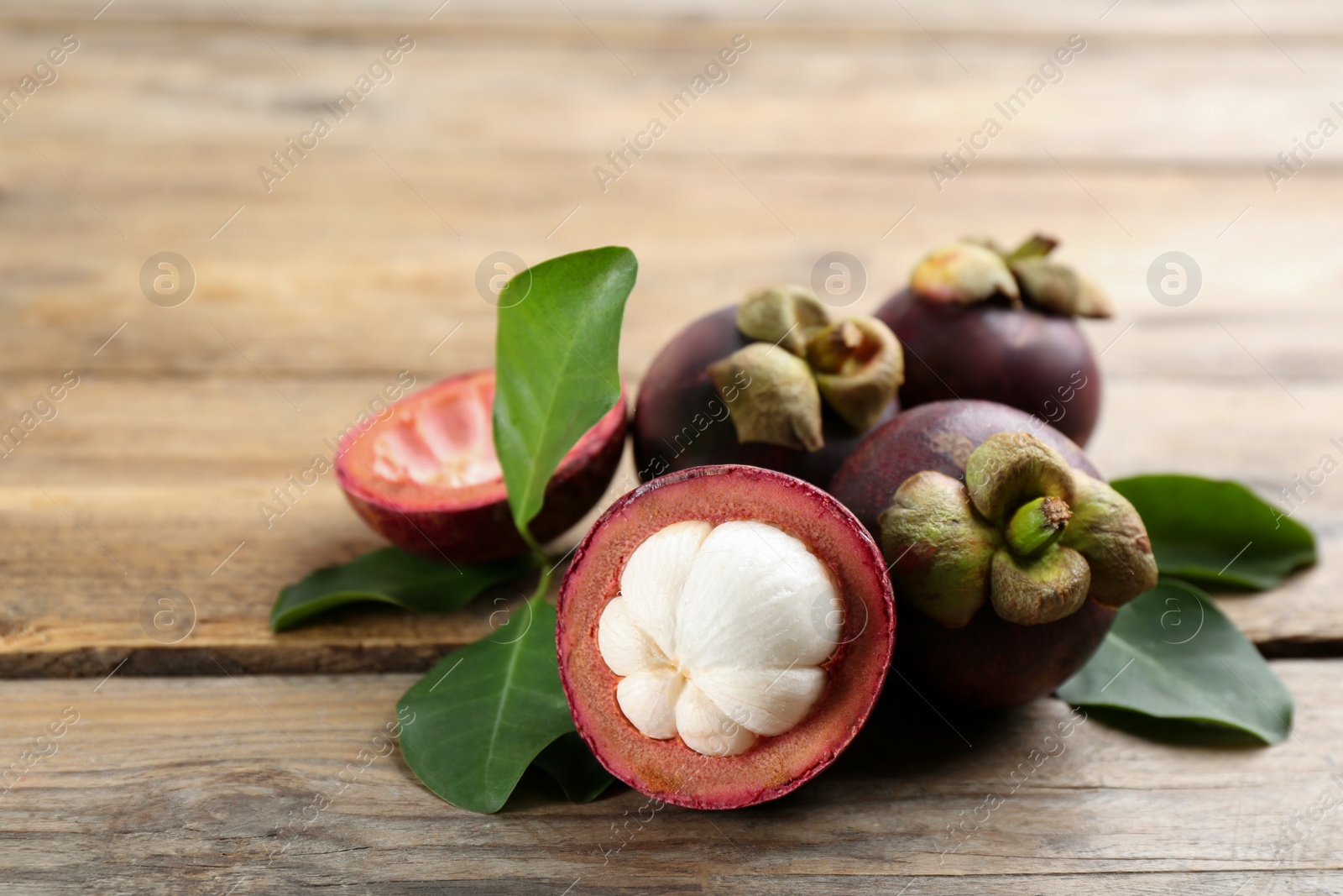 Photo of Delicious tropical mangosteen fruits on wooden table