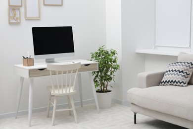 Photo of Spacious workspace with desk, chair, computer and potted plants at home