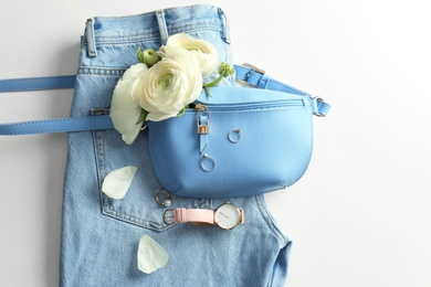 Photo of Flat lay composition with stylish bump bag and spring flowers on light background. Space for text