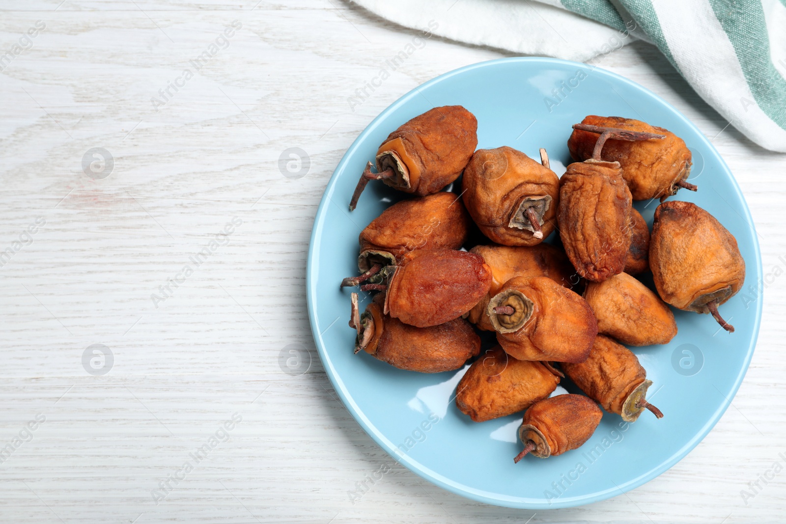 Photo of Plate with tasty dried persimmon fruits on white wooden table, flat lay. Space for text